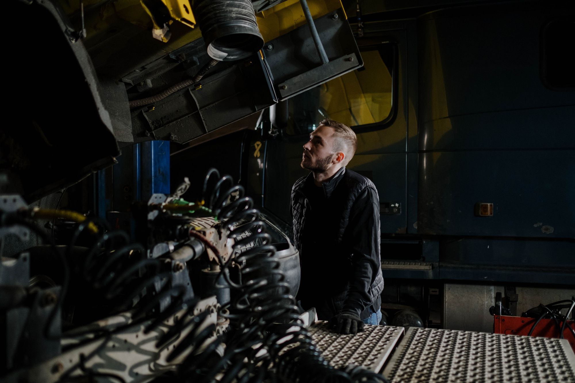 Technician inspecting a heavy-duty truck with the hood open in the shop